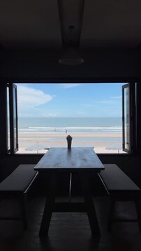 View through open window of a beach cafe looking at ocean waves and blue sky