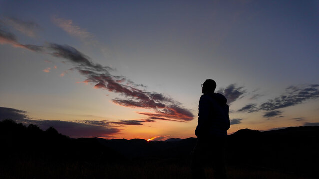 Silhouette of a man looking at the mountain sunset.