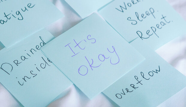 Blue sticky notes with handwritten messages about emotional fatigue, burnout, and mental health support