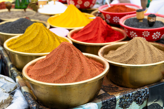Colorful ground spices piled in brass bowls at a traditional bazaar in Bukhara, Uzbekistan. Ideal for travel, cuisine, and cultural content.