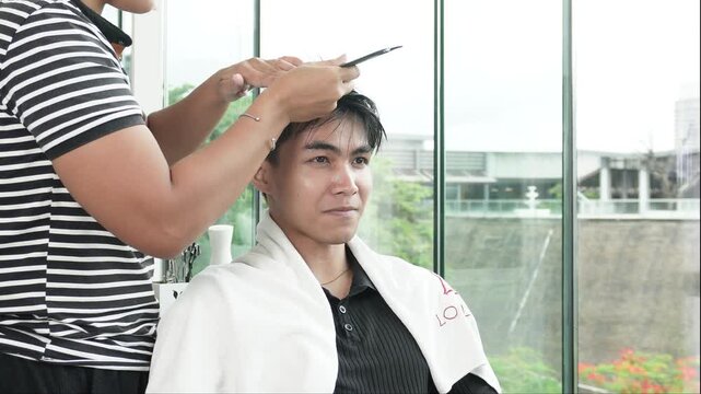 Hair stylist applying protein color cream before professional cellophane hair treatment for Southeast Asian man in his early 20s