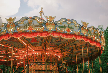 Classic vintage amusement park carousel top illuminated with golden lights outdoors © Anastasia