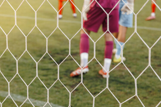 Dynamic soccer action seen through goal net, football ball hitting mesh during match in professional sports stadium competition concept