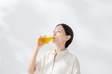 Naklejka na ściany i meble ペットボトルのお茶を飲む女性