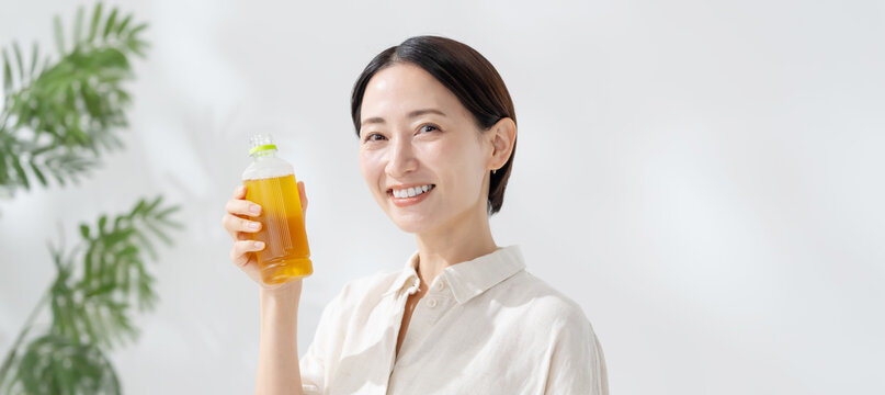 ペットボトルのお茶を飲む女性
