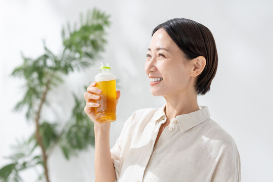 ペットボトルのお茶を飲む女性