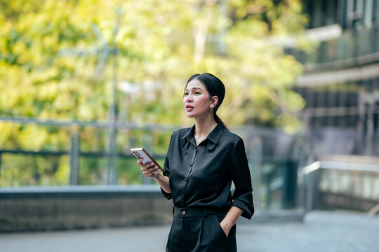 Businesswoman checking smartphone after phone call in office district. Professional using mobile technology for business communication, work updates and digital productivity.