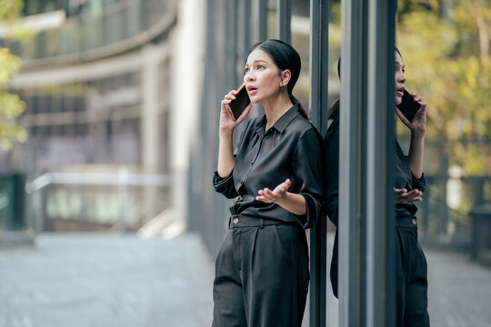 Businesswoman explaining ideas during smartphone conversation outside office. Professional discussing business matters, solving problems, communicating with clients and working remotely.