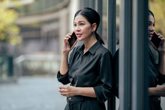 Close up businesswoman talking on smartphone outside office building. Professional communicating with clients, coordinating business tasks and using mobile technology for work.
