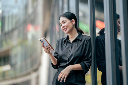 Businesswoman reviewing information on smartphone in modern business district. Professional accessing digital documents, business updates and mobile communication while working remotely.