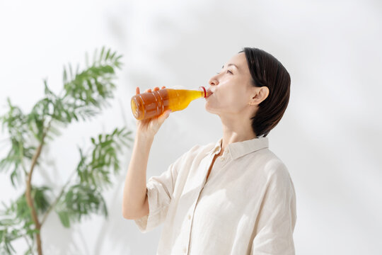 ペットボトルのお茶を飲む女性