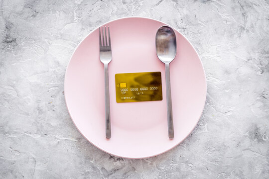 Meal is over. Pay bills. Bank card on empty plate on grey stone table top view