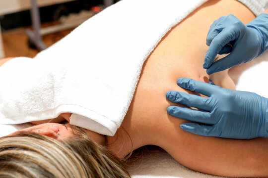 Therapist performing shoulder massage on a relaxed woman in a clinic