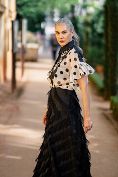 Graceful woman with charming attire. Sophisticated mature woman strolling through cityscape