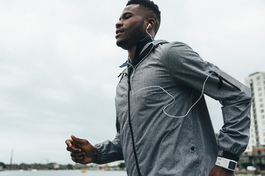 Young man running with earbuds and smartwatch