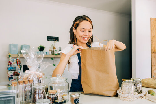 Smiling entrepreneur packing a shopping bag in a zero waste store