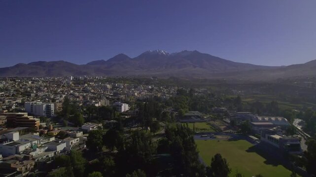 Aerial view of Arequipa city with Misti volcano, surrounded by residential buildings, green parks, and the Andes mountains in Arequipa, Arequipa, Peru.