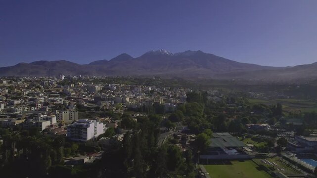 Aerial view of the city of Arequipa with the snow-capped Misti volcano in the background, featuring urban architecture, residential areas, and lush green spaces in Arequipa, Arequipa, Peru.