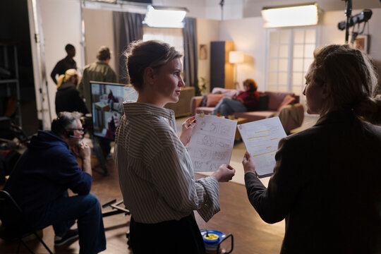 Female director discusses script with crew on film set