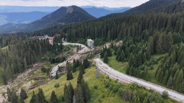 erial close-up of mountain landslide showing fallen trees and destroyed road near building