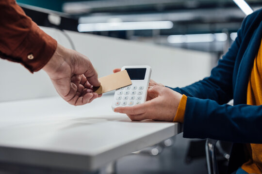 Hand of businessman paying on POS system at office