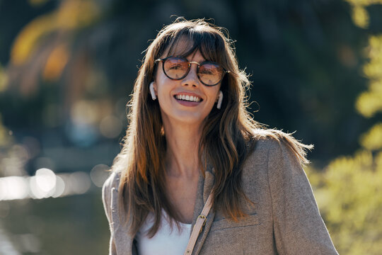 A happy woman listens to music with an earphone in the park