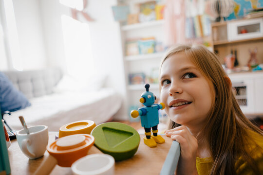 Girl at home playing with toy robot