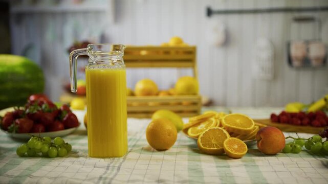 Tracking shot of beautiful, fresh oranges and pitcher of juice in kitchen