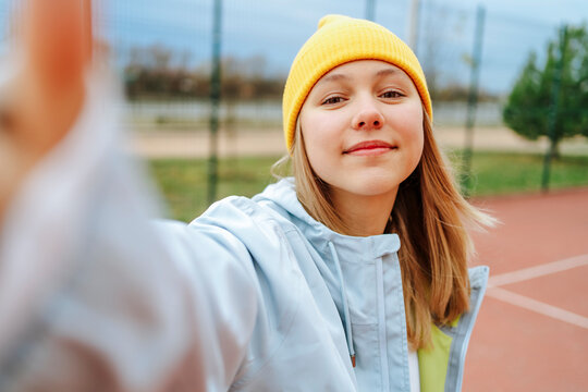 Smiling girl wearing knit hat taking selfie on playground