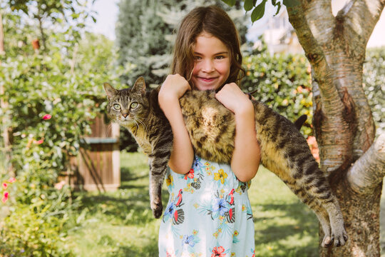 Girl holding cat in garden