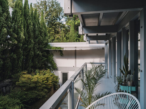 Modern balcony with chair overlooking lush green garden of a villa
