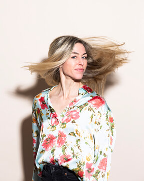 Smiling model tossing blonde hair wearing a floral silk shirt