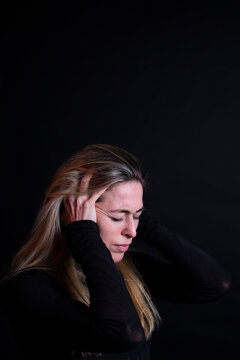 Patient indoor holding head in pain against dark background