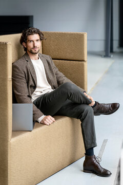 Businessman sitting with laptop on seat at office