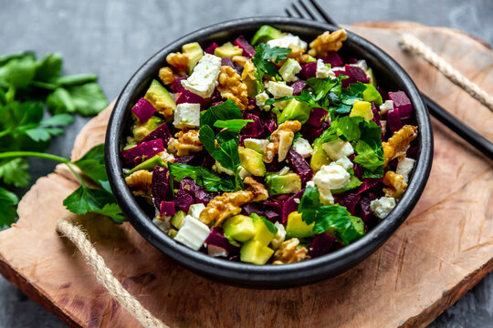 Bowl of beetroot salad with avocado, feta, walnuts and parsley