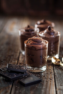 Glasses of vegan mousse au chocolat and bittersweet chocolate on wood