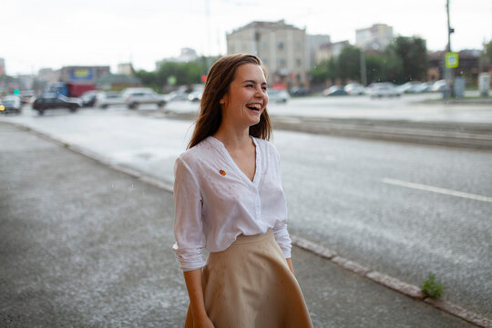 Happy woman laughing in the rain on a city street during summer