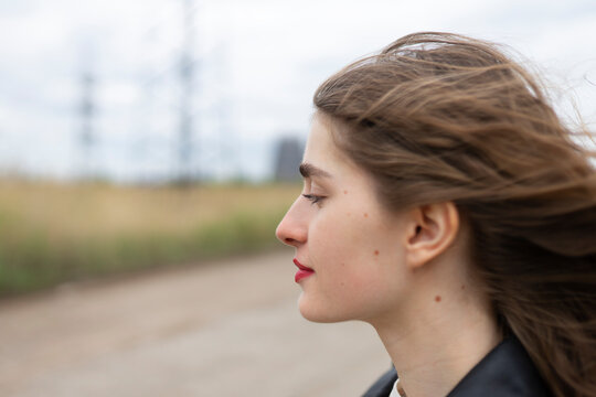 Woman in leather jacket feels the wind outdoors