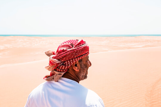 Bedouin in National dress standing in the desert, rear view, Wahiba Sands, Oman