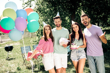 Obraz premium Friends celebrating a summer birthday outdoors with colorful balloons, cake and gifts at a backyard party