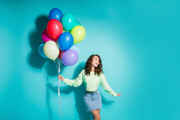 Obraz premium Young woman holding colorful balloons against turquoise background smiling and celebrating with joyful, playful energy — lifestyle party portrait conveying happiness, freedom, fun and colorful 