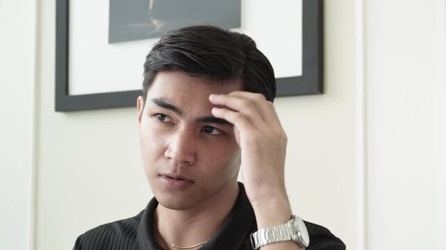 Young man admiring his new hairstyle after professional cellophane treatment and rebonding in salon for Southeast Asian man in his early 20s
