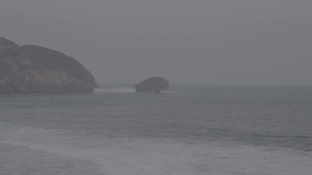 A view of the sea cliffs, with waves crashing repeatedly against the rocky cliffs. There's a large rocky island in the middle. Panoramic view, S-Log3, S-Gamut3.Cine