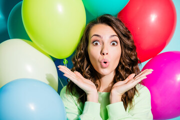 Obraz premium Surprised young woman with colorful balloons celebrating at a playful party moment, joyful expression and festive mood for birthday or celebration concepts