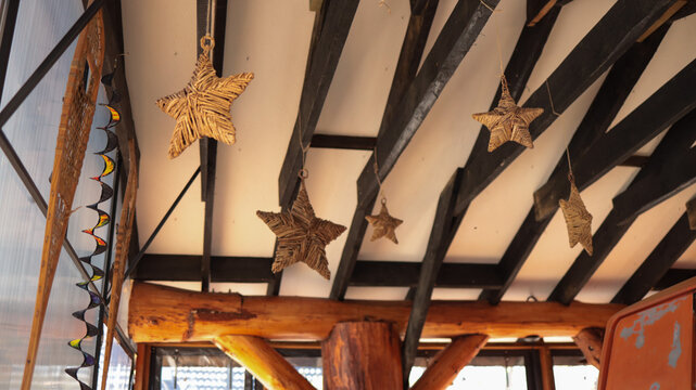 Wooden roof beam structure decorated with hanging star ornaments and cozy string lights indoors. JPG