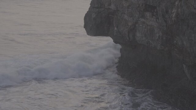 A view of the sea cliffs, with waves crashing repeatedly, rocky cliffs. The blue sea in the afternoon. Elevated View, S-Log3, S-Gamut3.Cine