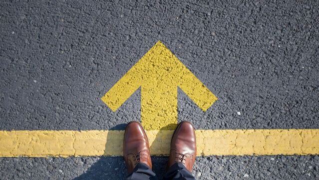 Professional standing on painted road marker signaling directional growth with progress direction decision business pavement opportunity pointing leadership motivation strategy commitment