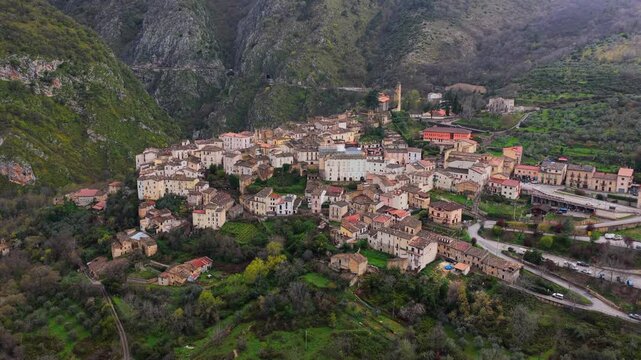 Aerial view of the historic stone village of Anversa degli Abruzzi nestled in the mountains with lush green hills and valley surroundings in Anversa degli Abruzzi, Abruzzo, Italy.