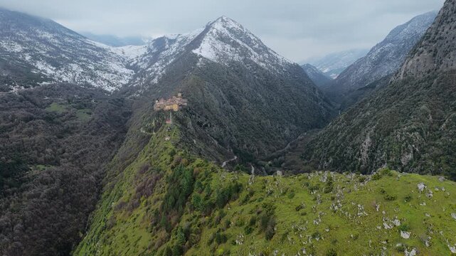 Aerial view of the historic village of Anversa degli Abruzzi perched on a mountain ridge with snow-capped peaks and lush green valleys in Anversa degli Abruzzi, Abruzzo, Italy.
