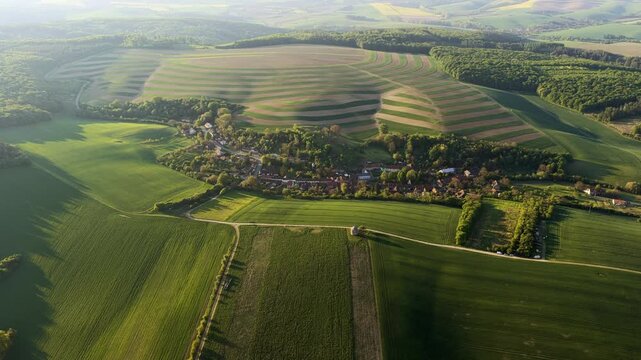 Aerial view of rolling green fields and agricultural patterns surrounding the village of Chvalkovice, Hradec Kralove Region, Czechia.